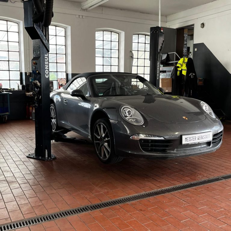 Grauer Porsche 911 steht auf einer Hebebühne in einer Werkstatt.