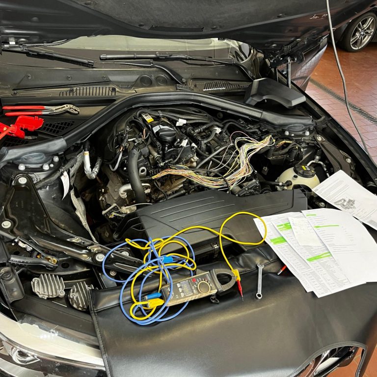 Motorausbau mit Kabeln, Multimeter und technischen Unterlagen auf einem Fahrzeug.